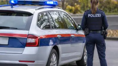 KI-generiertes Bild: Eine uniformierte Polizeikraft steht neben einem silbernen Streifenwagen.