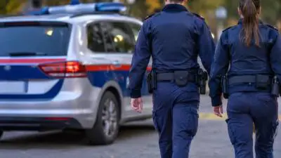 KI-Symbolbild: Uniformierte Personen gehen neben einem Einsatzfahrzeug.