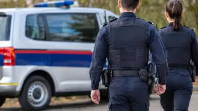 KI-generiertes Bild: Uniformierte Personen stehen vor einem weiß-blauen Fahrzeug mit Dachleuchte.
