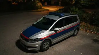 KI-Symbolbild: Ein silberner Kombi mit blau-roten Streifen steht nachts auf einer Straße.
