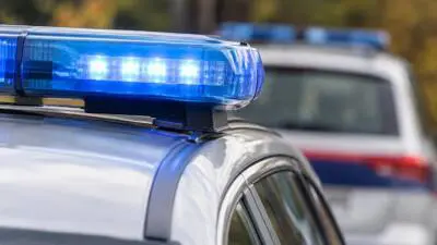 KI-Symbolbild: Nahaufnahme eines weißen Autos mit blauem Blaulicht.