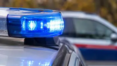 KI-Symbolbild: Ein blaues Warnlicht auf einem weißen Fahrzeug, dahinter ein weiteres Auto.
