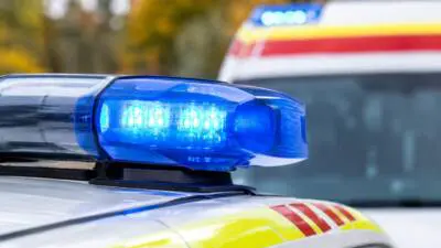 KI-generiertes Bild: Ein blaues Warnlicht auf einem weiß-gelben Einsatzfahrzeug vor unscharfem Hintergrund.