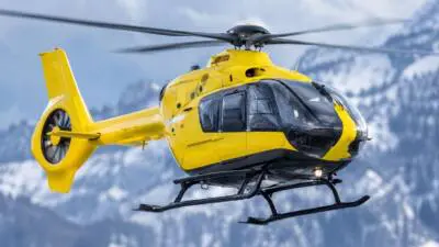 KI-Symbolbild: Ein gelber Hubschrauber vor verschneiten Bergen.