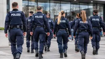 KI-generiertes Bild: Uniformierte Personen gehen vor einer Glasfassade.
