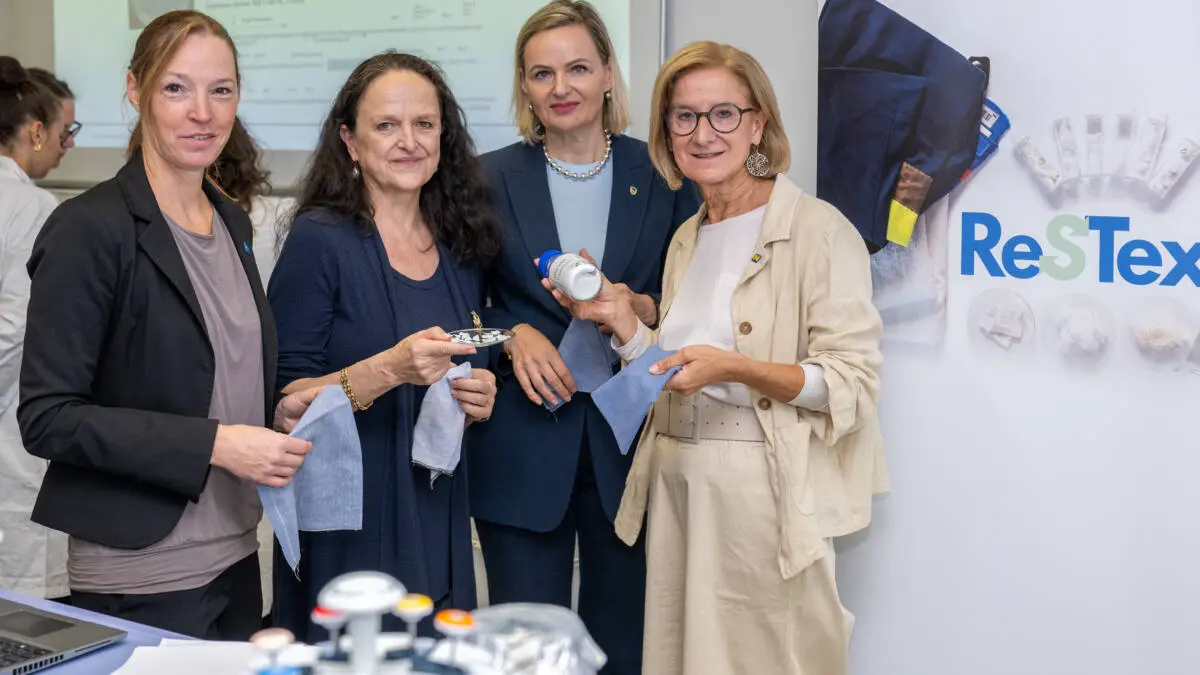 Frauen präsentieren Stoffproben vor einer ReSTex-Ausstellung zur Textilforschung.