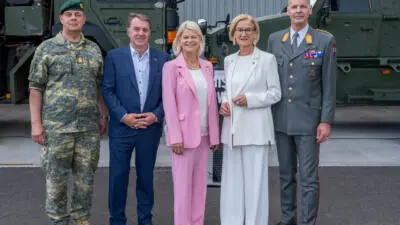 Eine Gruppe steht vor Militärfahrzeugen; der Beitrag berichtet über Beschaffungsvorhaben des Bundesheeres.