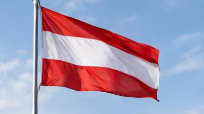 KI-Symbolbild: Eine österreichische Fahne weht an einem Mast vor blauem Himmel.