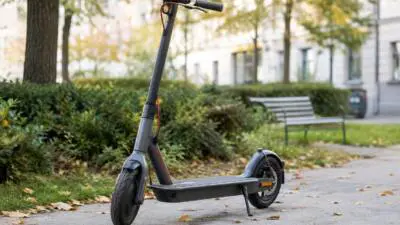 KI-generiertes Bild: Ein dunkler E-Scooter steht auf einem gepflasterten Weg in einer Grünanlage.