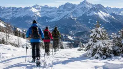 KI-generiertes Bild: Wandernde mit Stöcken auf einem verschneiten Bergweg vor schneebedeckten Alpen.