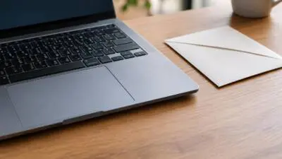 KI-generiertes Bild: Ein geöffneter Laptop, ein weißer Umschlag und eine Tasse stehen auf einem Holztisch.