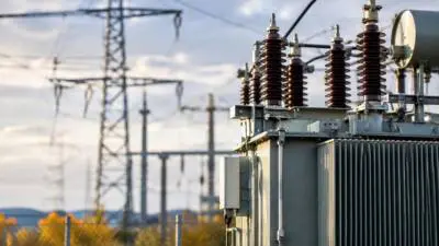 KI-generiertes Bild: Ein Transformator mit Isolatoren vor Strommasten und Leitungen.