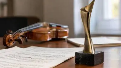 KI-Symbolbild: Eine goldfarbene Trophäe steht neben einer Violine und Notenblättern.