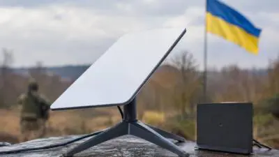 KI-Symbolbild: Eine Satellitenantenne steht vor einer ukrainischen Flagge.
