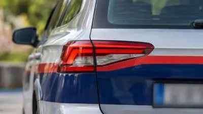 KI-Symbolbild: Heck eines silbernen Fahrzeugs mit rot-blauen Streifen.