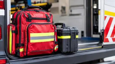 KI-generiertes Bild: Eine rote Tasche mit Reflexstreifen und ein schwarzer Koffer liegen auf der Ladefläche eines Fahrzeugs.