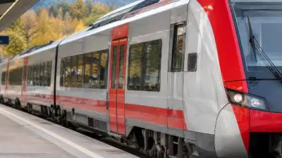 KI-generiertes Bild: Ein rot-grauer Zug steht an einem Bahnsteig.