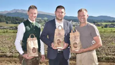 Drei Männer präsentieren Säcke mit Bio-Eachtling auf einem Feld; SPAR bietet die Lungauer Bio-Kartoffeln wieder an.