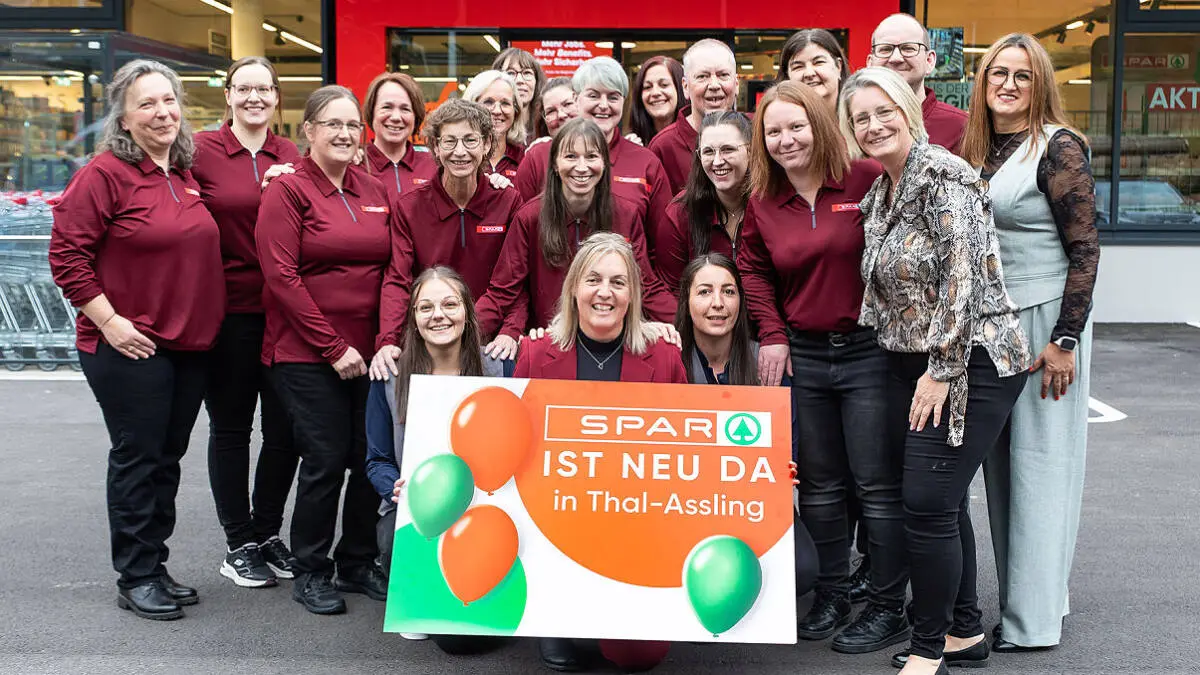 Eine Gruppe präsentiert vor dem neuen SPAR-Markt in Thal-Assling ein Schild zur Eröffnung.
