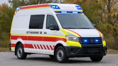 KI-generiertes Bild: Ein weißer Rettungswagen mit roten und gelben Streifen steht auf einer Straße.