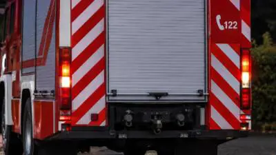 KI-generiertes Bild: Rückansicht eines roten Feuerwehrfahrzeugs mit rot-weißen Markierungen.