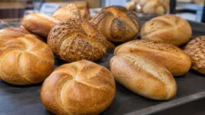 KI-generiertes Bild: Verschiedene goldbraune Semmeln liegen auf einer dunklen Ablage.