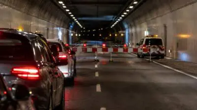 KI-Symbolbild: Autos stehen vor einer Schranke in einem beleuchteten Tunnel.