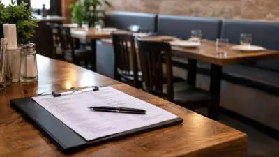 Ein Klemmbrett mit Formular und Stift liegt auf einem Holztisch im Restaurant.