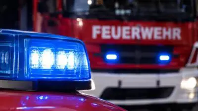 KI-generiertes Bild: Ein blaues Warnlicht leuchtet vor einem roten Feuerwehrfahrzeug.