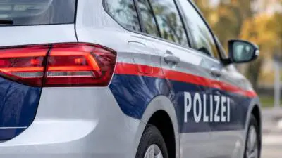 KI-generiertes Bild: Ein silbernes Polizeiauto mit blau-roter Beklebung und der Aufschrift „POLIZEI“.