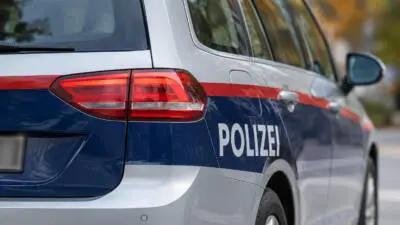 KI-generiertes Bild: Seitliche Nahaufnahme eines silber-blauen Polizeiautos mit rotem Streifen und POLIZEI-Aufschrift.