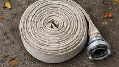 KI-generiertes Bild: Ein aufgerollter Feuerwehrschlauch liegt auf Asphalt.