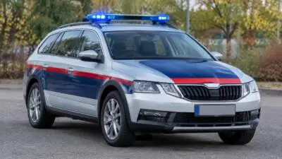 KI-Symbolbild: Ein silberner Kombi mit blauem Blaulicht steht auf einer Straße.