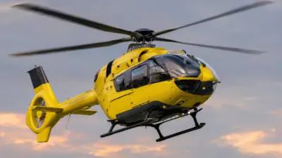 KI-Symbolbild: Ein gelber Hubschrauber vor einem wolkigen Himmel.