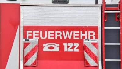 Rote Rückseite eines Feuerwehrfahrzeugs mit Aufschrift Feuerwehr und Notrufnummer 122
