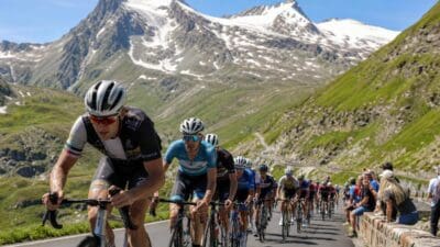 Radrennfahrer auf einer Bergstraße vor schneebedeckten Alpengipfeln bei der Tour of Austria