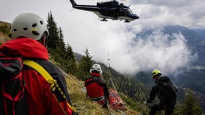 Rettungskräfte sichern verletzten Piloten bei Hubschrauberbergung am steilen Berghang