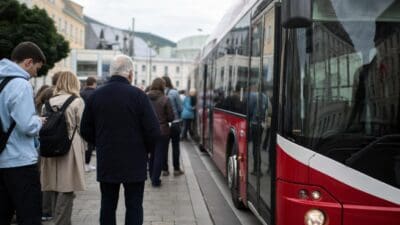 Menschen warten in einer Schlange neben einem roten Bus auf der Straße