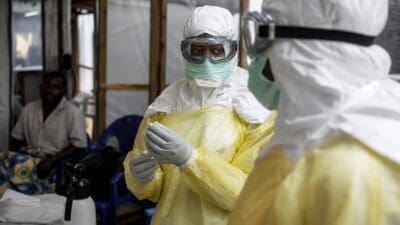 Medizinische Helferin in gelber Schutzkleidung und mit Schutzbrille in einem Behandlungsraum während des Ebola-Ausbruchs