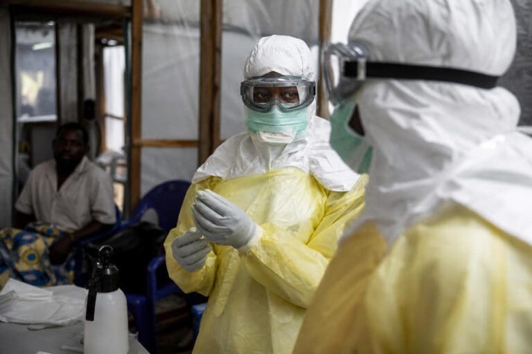 Medizinische Helferin in gelber Schutzkleidung und mit Schutzbrille in einem Behandlungsraum während des Ebola-Ausbruchs