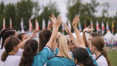 Gruppe junger Sportlerinnen in türkisen Trikots hebt die Hände in die Höhe