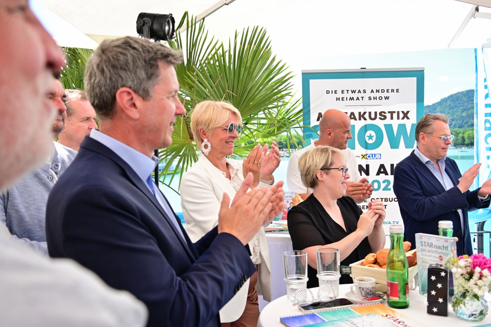 Gruppe von Menschen applaudiert bei einer Veranstaltung am Wörthersee unter einem Zelt