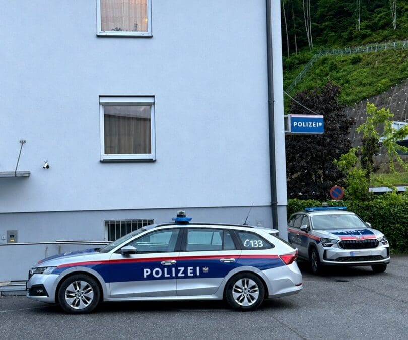 Zwei Polizeifahrzeuge parken vor einem hellen Gebäude mit Polizeischild