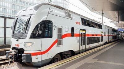 Weiß-roter Doppelstockzug der ÖBB steht am Bahnsteig eines Bahnhofs