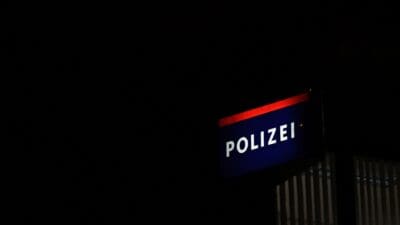 Beleuchtetes Polizeischild mit der Aufschrift Polizei vor dunklem Nachthimmel
