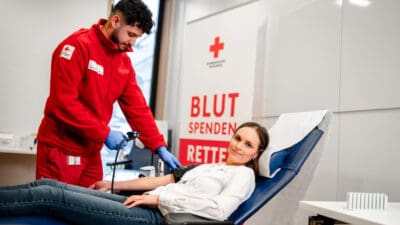 Mitarbeiter des Roten Kreuzes betreut eine Blutspenderin in einem Spendestuhl