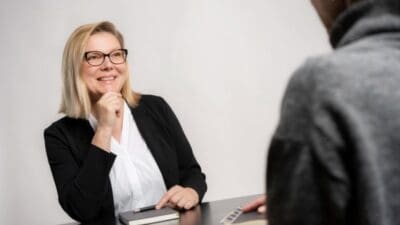 Kathrin Stainer-Hämmerle lächelt während eines Gesprächs am Tisch mit Notizbuch