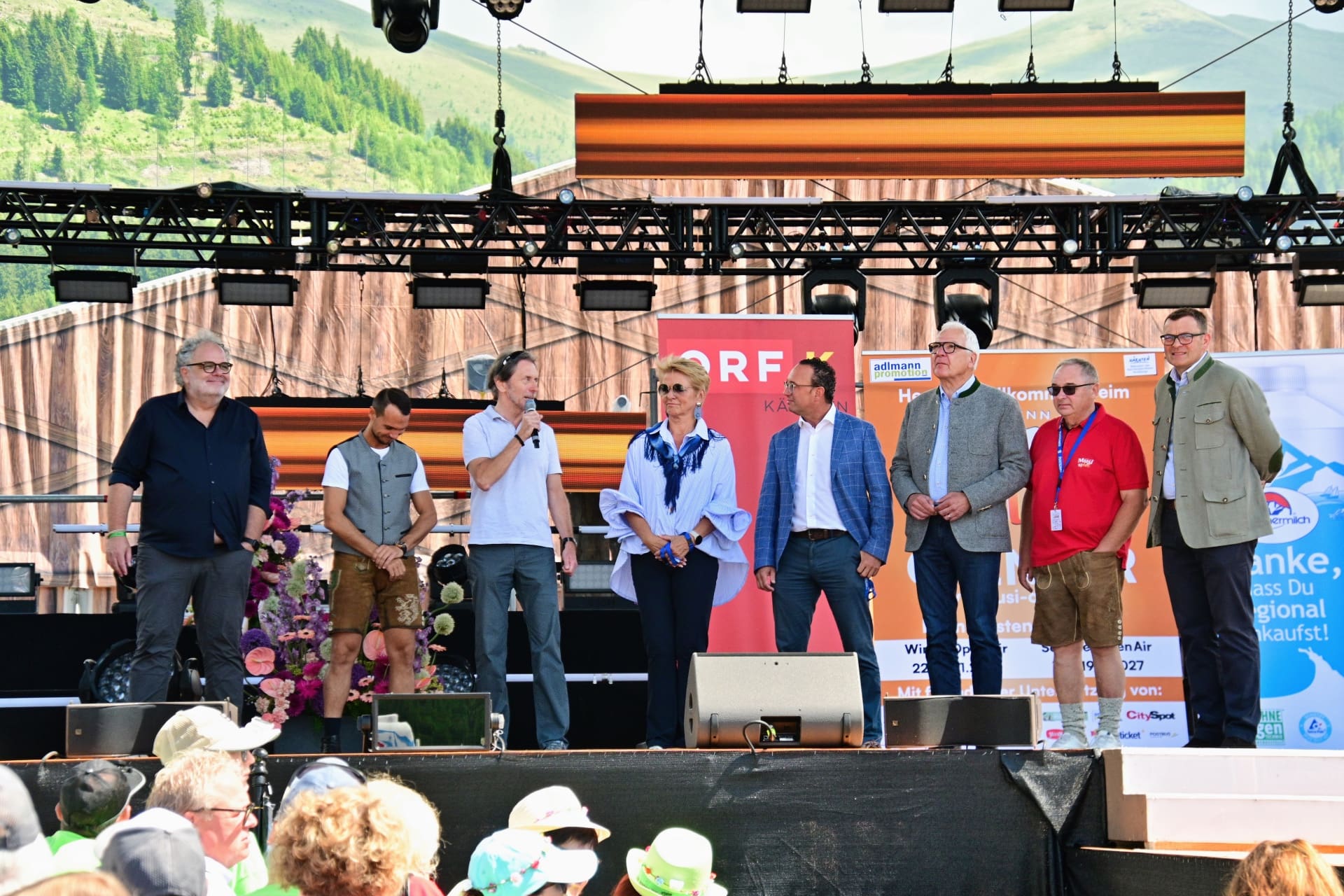Mehrere Personen stehen auf einer Bühne bei einer Veranstaltung vor Bergkulisse und ORF-Logo