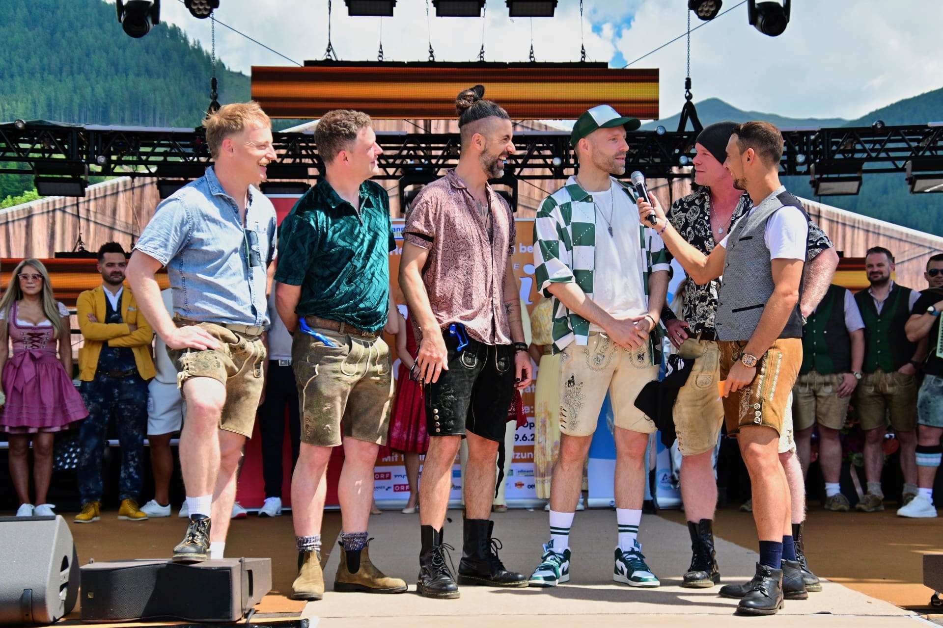 Mehrere Männer in Tracht auf einer Bühne bei einem Open-Air-Festival in den Bergen