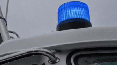 Blaues Blaulicht auf dem nassen weißen Dach eines Wasserrettungsbootes
